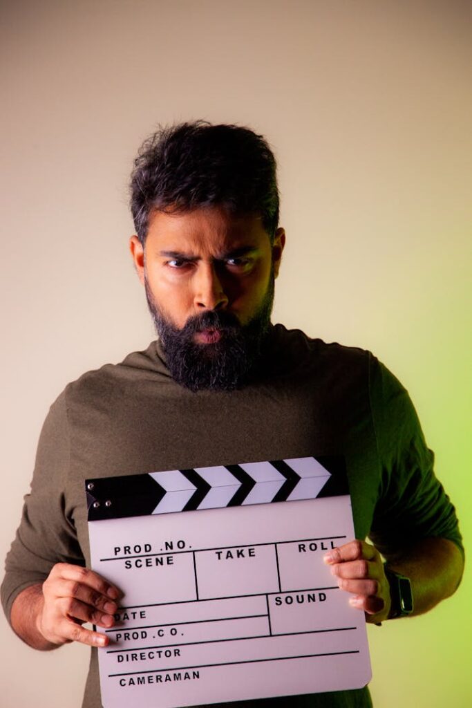 A serious bearded man holding a clapperboard, ready for a film studio shoot.