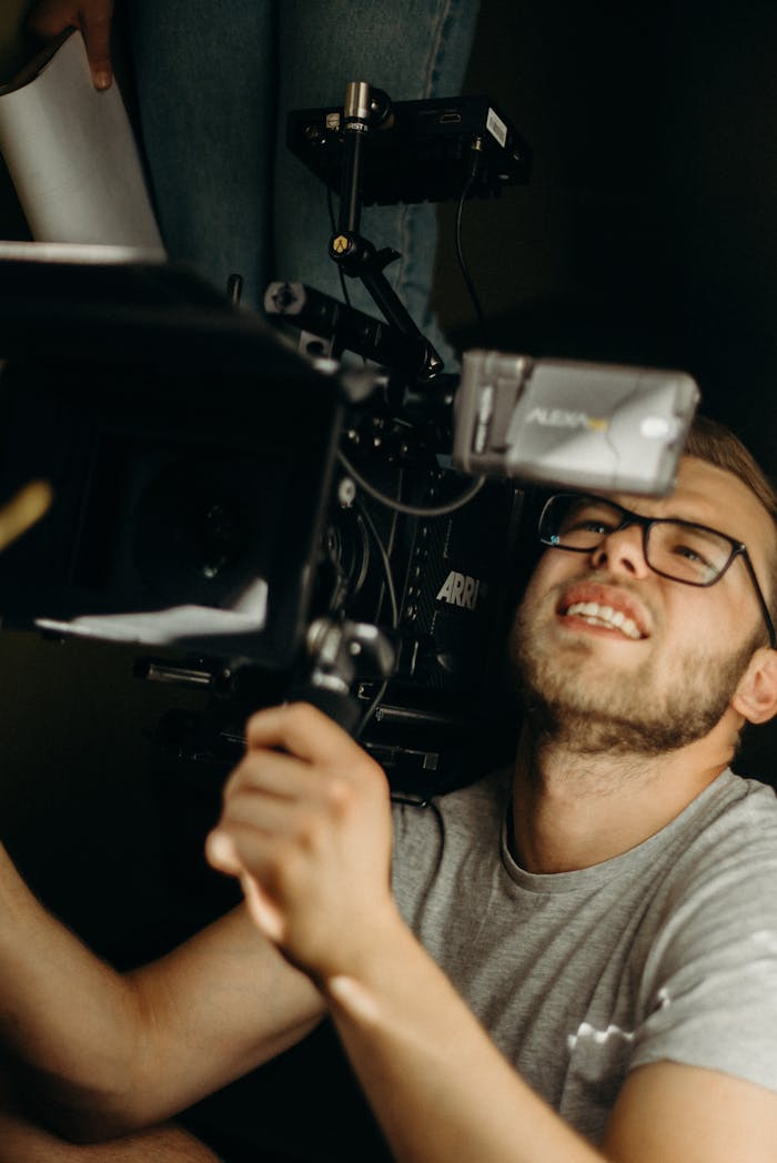 Professional cinematographer adjusting a camera on a film set indoors.
